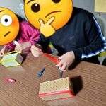 おみくじづくりのため、箱にテープを貼っている子ども